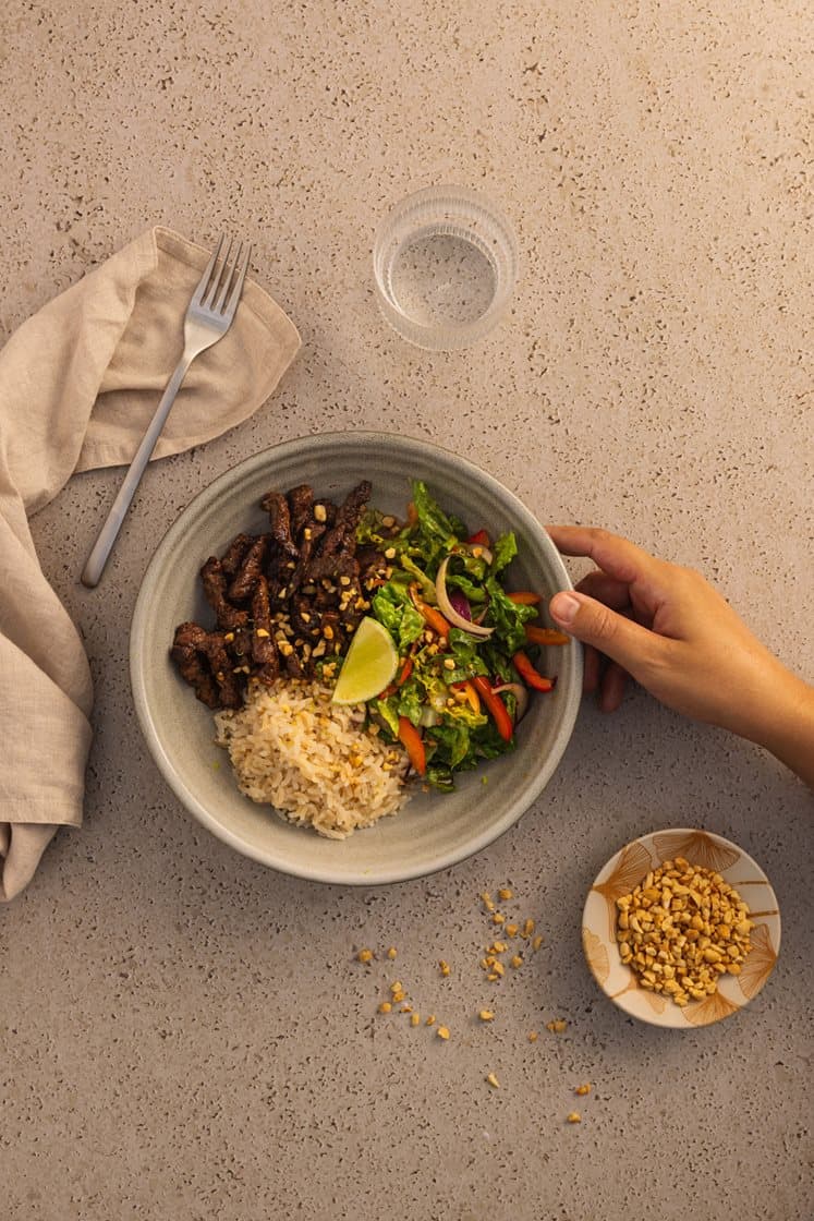 Thaisalat med oksetykstegsbøffer og friske grøntsager, serveret med peanuts og fuldkornsris