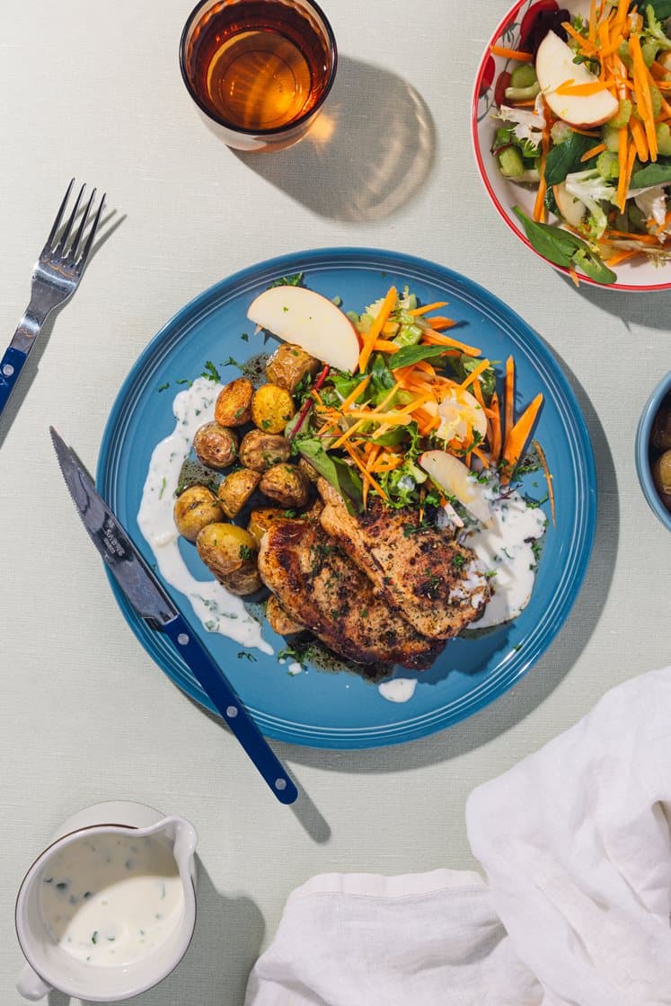 Svinekoteletter med persillesauce, krydderkartofler og æblesalat