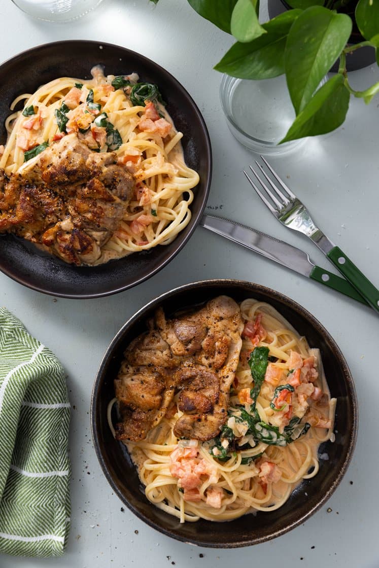 Citruskrydret kyllingelårsteak og pasta i cremet sauce med spinat og tomat