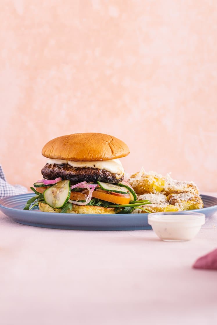 Trøffelburger med mozzarella, smashede krydderkartofler, syltet agurk, rucola og tomat